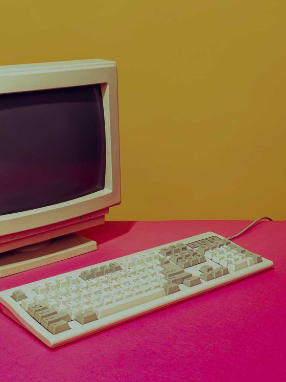 vintage computer monitor and keyboard on bright pink