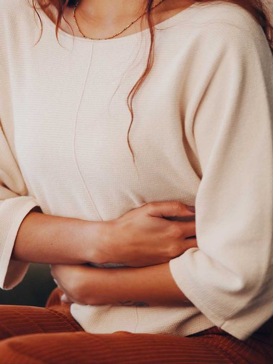 woman with endometriosis clutching hands near stomach