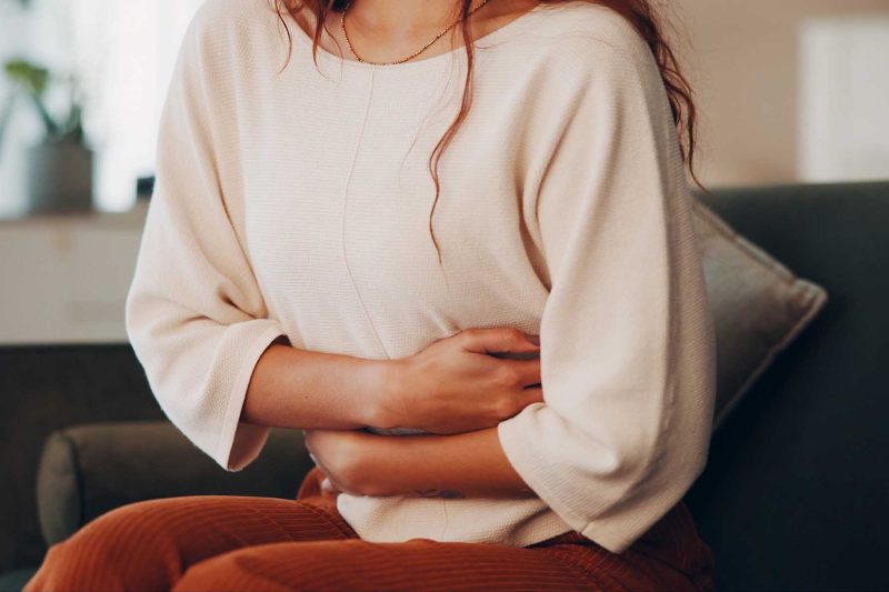 woman with endometriosis clutching hands near stomach