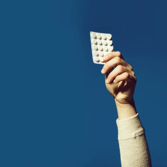 womans hand holding blister ack of antidepressant tablets in air