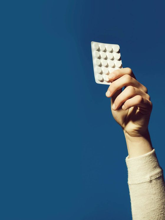 womans hand holding blister ack of antidepressant tablets in air